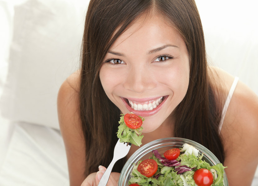 a woman smiling eating a healthy salad