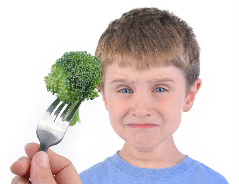 school age boy not looking happy to eat broccoli