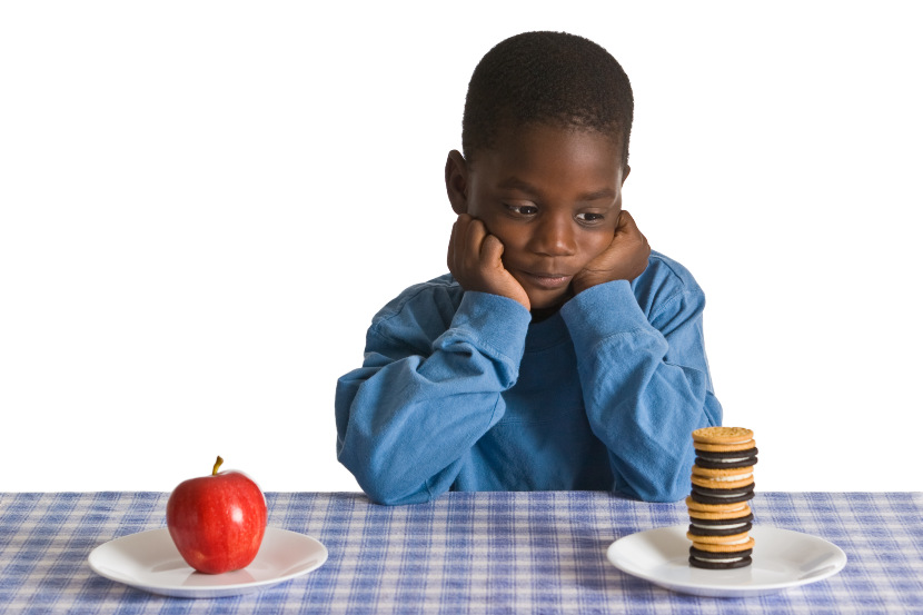 boy deciding between healthy food and dessert