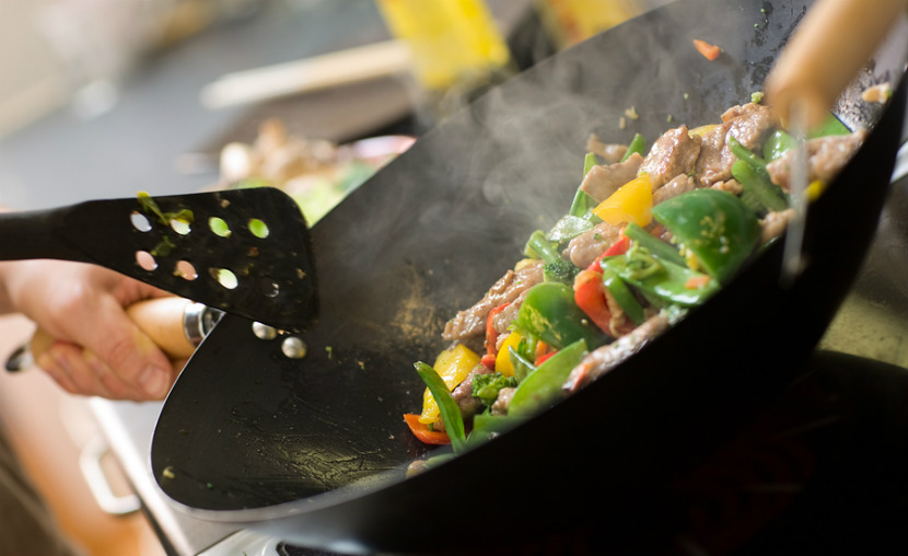 beef and vegetable stir fry being cooked in a wok